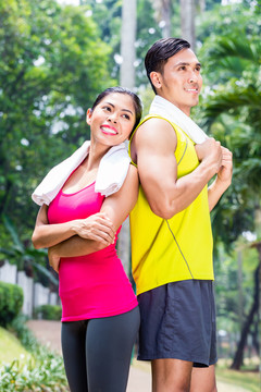 亚洲女子和男子在慢跑训练中用毛巾并肩站立