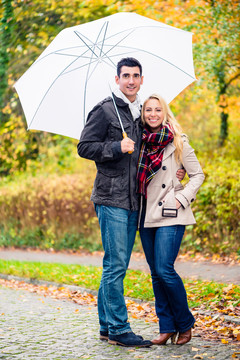 情侣们在雨中散步，享受着秋天的快乐，树叶五彩缤纷