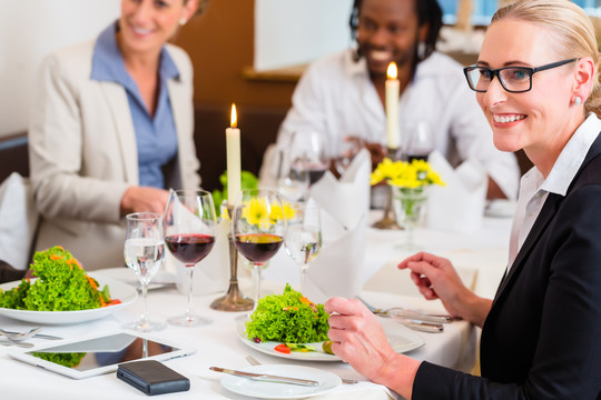 团队中的商务人士在餐厅用餐，餐桌上摆着食物和酒