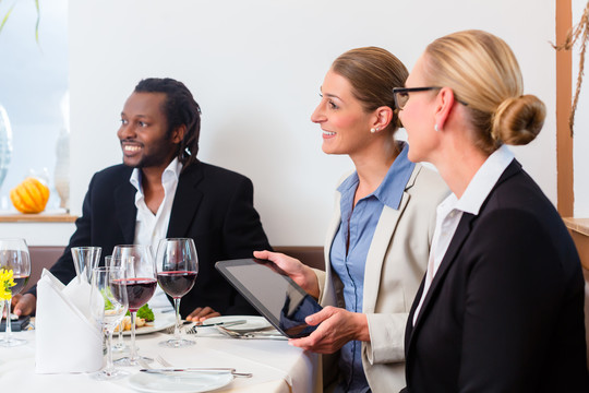 商务午餐团队会议在餐厅吃喝玩乐，共同庆祝良好的工作关系，食物和饮料放在桌子上的背景