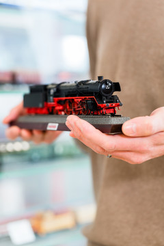 在玩具店里买铁路模型的人手里拿着模型，特写镜头
