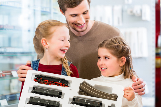 一家人在玩具店买火车模型，父亲带着两个孩子