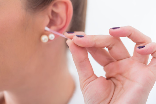 浴室里的女人正在用棉花棒清洁她的耳朵