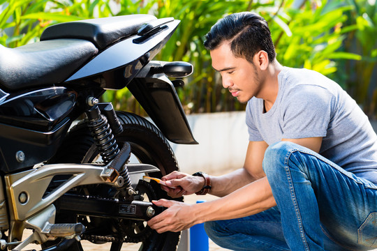 亚洲男子在花园里做摩托车维修