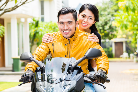 一对亚洲夫妇骑着摩托车，妻子坐在丈夫后面