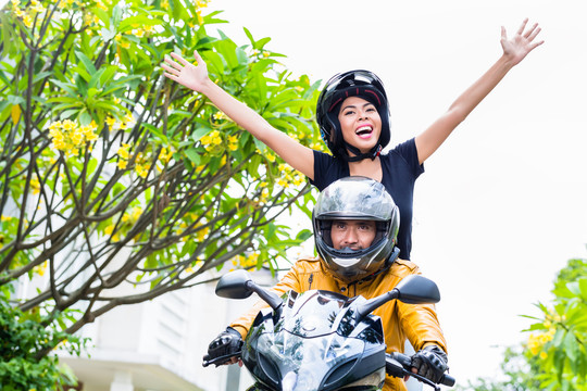 一名印尼妇女在摩托车上舒展双臂感到自由