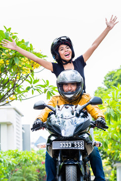 一名印尼妇女在摩托车上舒展双臂感到自由
