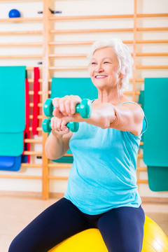 老年妇女在健身房用哑铃做健身运动