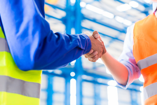 工人和工程师在工厂签订协议时握手