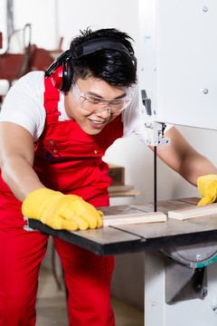 一名中国工人在一家工业工厂锯工件
