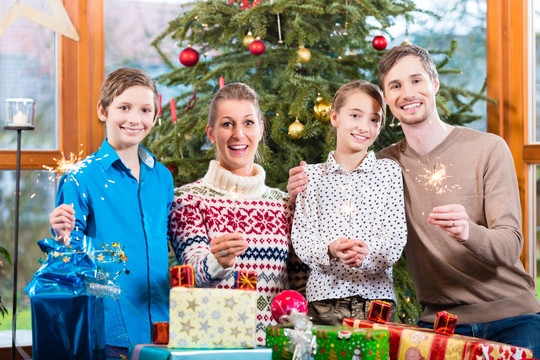 圣诞树下，妈妈、爸爸和孩子们带着礼物的幸福家庭