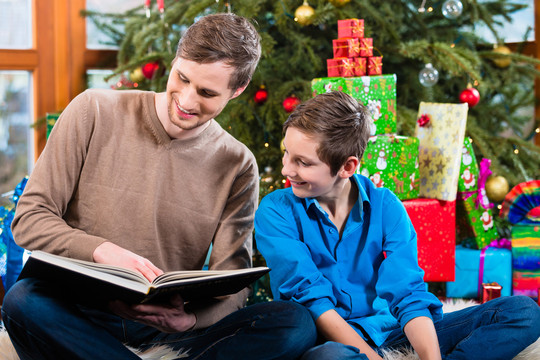 圣诞节，爸爸在圣诞树下为孩子朗读书