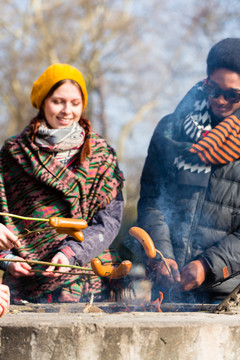 多民族的年轻人在寒冷的秋天在户外烤香肠
