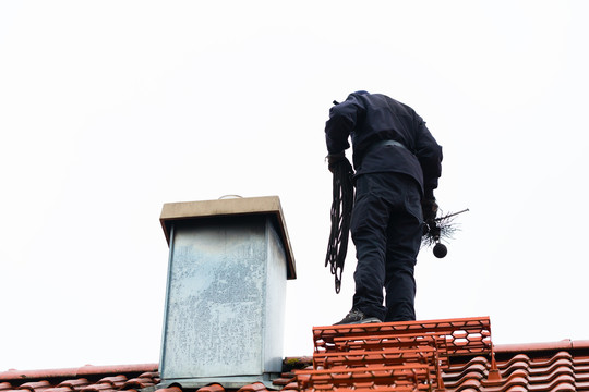 烟囱清扫器站在家里工作的屋顶上