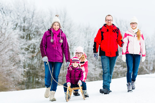一家人带着孩子在雪地里愉快地散步