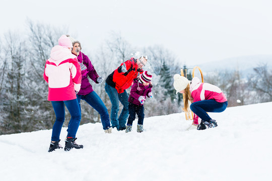 一家人带着孩子在冬天打雪仗，玩得很开心