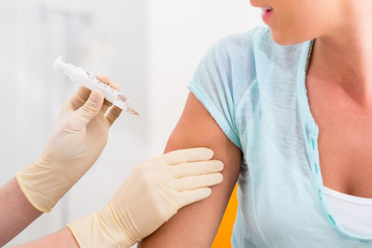 一名妇女在看医生，手臂上拿着疫苗注射器