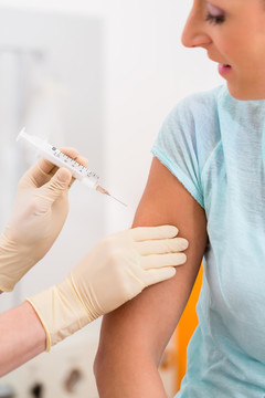 一名妇女在看医生，手臂上拿着疫苗注射器