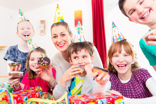 孩子们和所有的朋友和妈妈一起在大型聚会上吃纸杯蛋糕庆祝生日