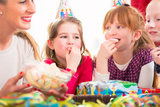 孩子们在生日派对上戴着派对帽啃糖果