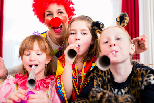 当一个小丑来访款待孩子们时，孩子们正在和噪音制造者一起庆祝生日聚会