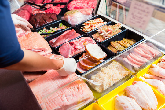 肉店的女售货员在展示不同种类的肉和香肠