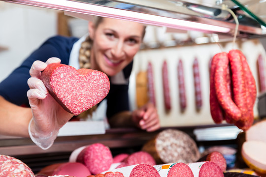 肉店女售货员向顾客展示心形香肠