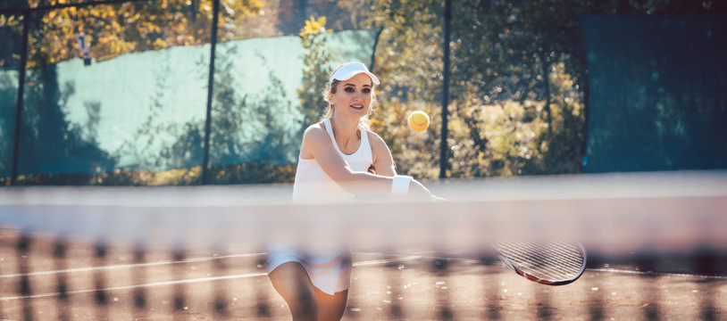 女运动员在网球场上接球