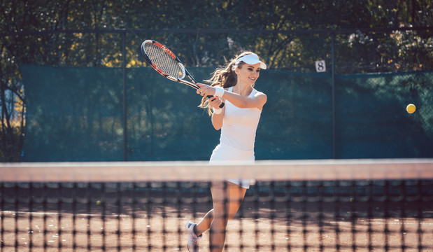 女子在球场上用力打网球