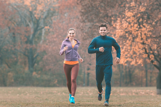 在美丽的秋天风景中，夫妻俩朝着镜头奔跑，以获得更好的体能