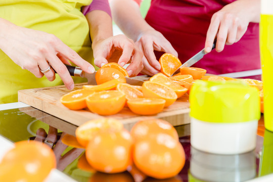 两名妇女用刀切成熟新鲜橙子的特写镜头