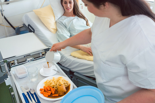 护士在医院为卧床病人提供食物，俯视图