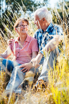 两个年长的女人和男人坐在草地上看着对方
