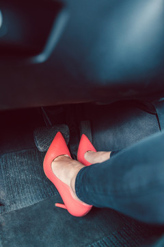 穿着红色高跟鞋以不安全的方式驾驶汽车的妇女