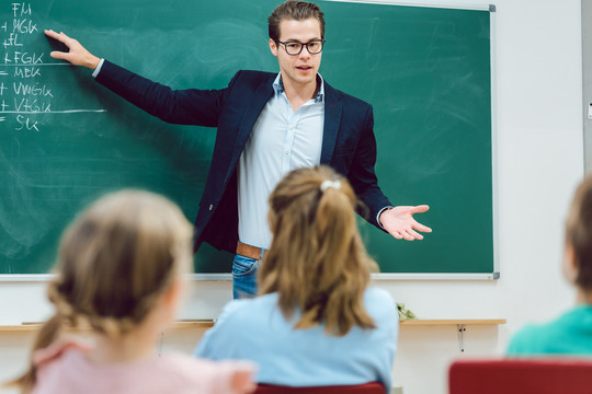 在学校课堂上，老师站在学生面前解释有趣的事情