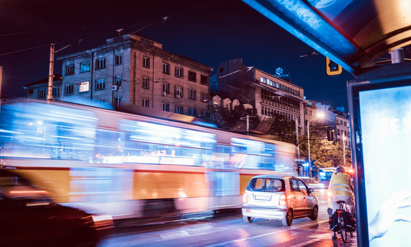 有轨电车在十字路口交通中的夜景，灯光轨迹运动模糊