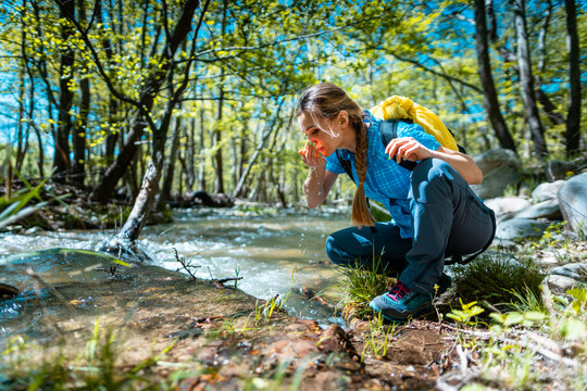 徒步旅行时，一位妇女正在用清溪的淡水提神