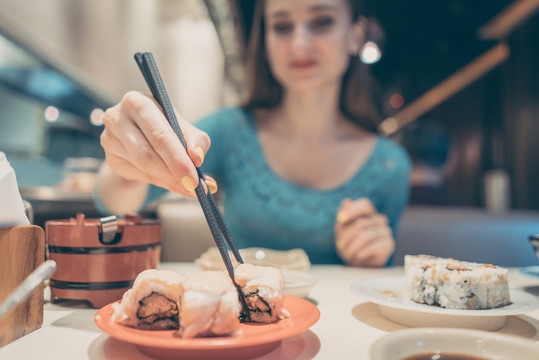 在日本餐馆用棍子吃寿司的女人