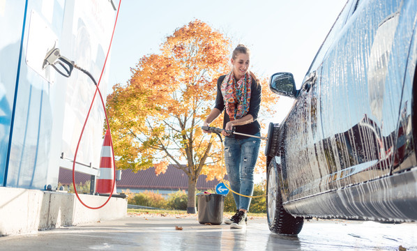 在自助洗车间用水清洗车辆的妇女