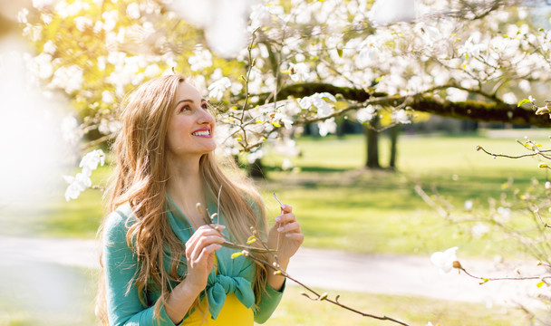 美丽的女人在树下的公园里享受春天的花朵