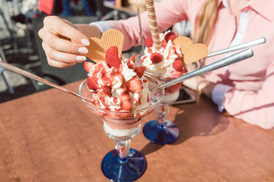阳光明媚的日子里，女人们在餐馆里吃着草莓冰淇淋