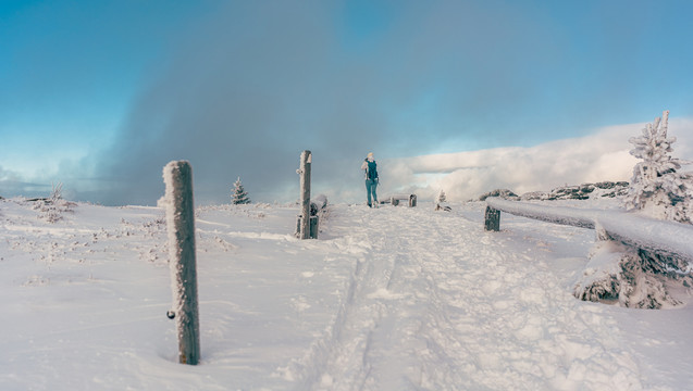 人们在蓝天下的寒冷和积雪中徒步穿越冬季景观