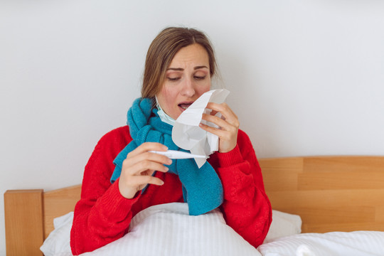 妇女感染2019冠状病毒疾病或卧病在床上看体温计