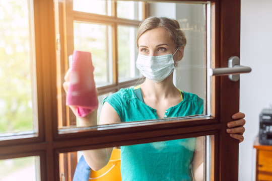 妇女在2019冠状病毒疾病的清洗期间，窗户被关上，因为生活还在继续，而邻居还在看着。