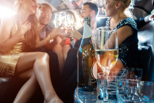 女人和男人在豪华轿车里用饮料庆祝，重点放在酒瓶上