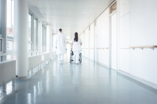 坐轮椅在医院走廊上行走的医生、护士和患者
