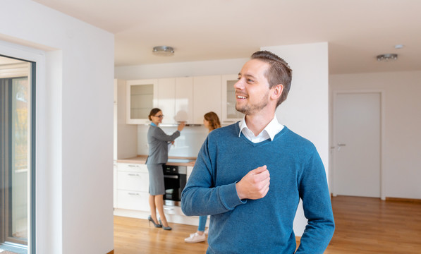 男人对他想买的新公寓感到满意，房地产经纪人和他的妻子在幕后