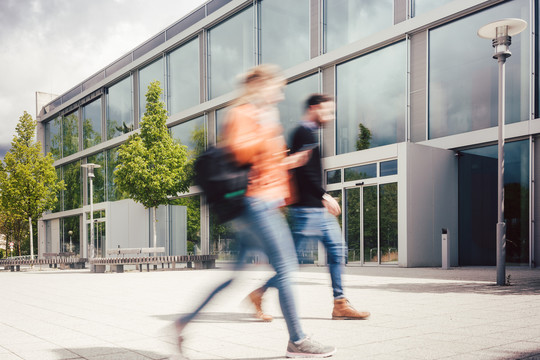 学生们在大学校园主建筑前忙碌的模糊轮廓