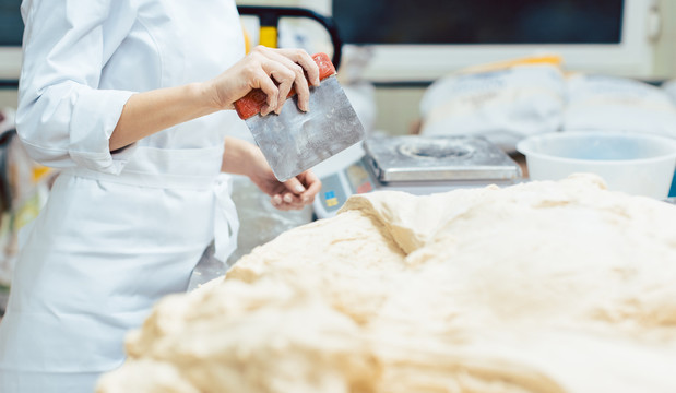 面包师测量和切割面团以制作面包