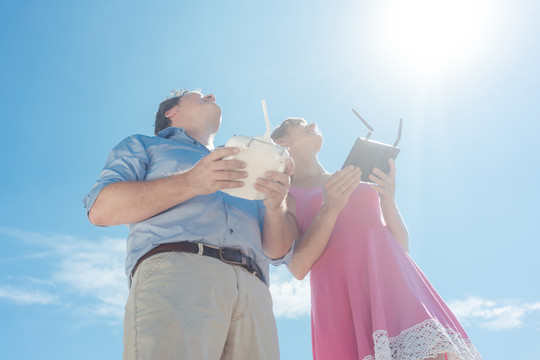 一个女人和一个男人操作着一架无人机，拍摄着仰望天空的照片